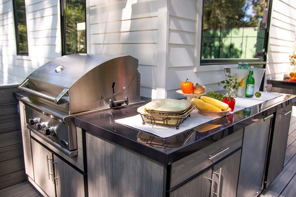 Outdoor kitchen with grill, countertop with food, and cabinets.