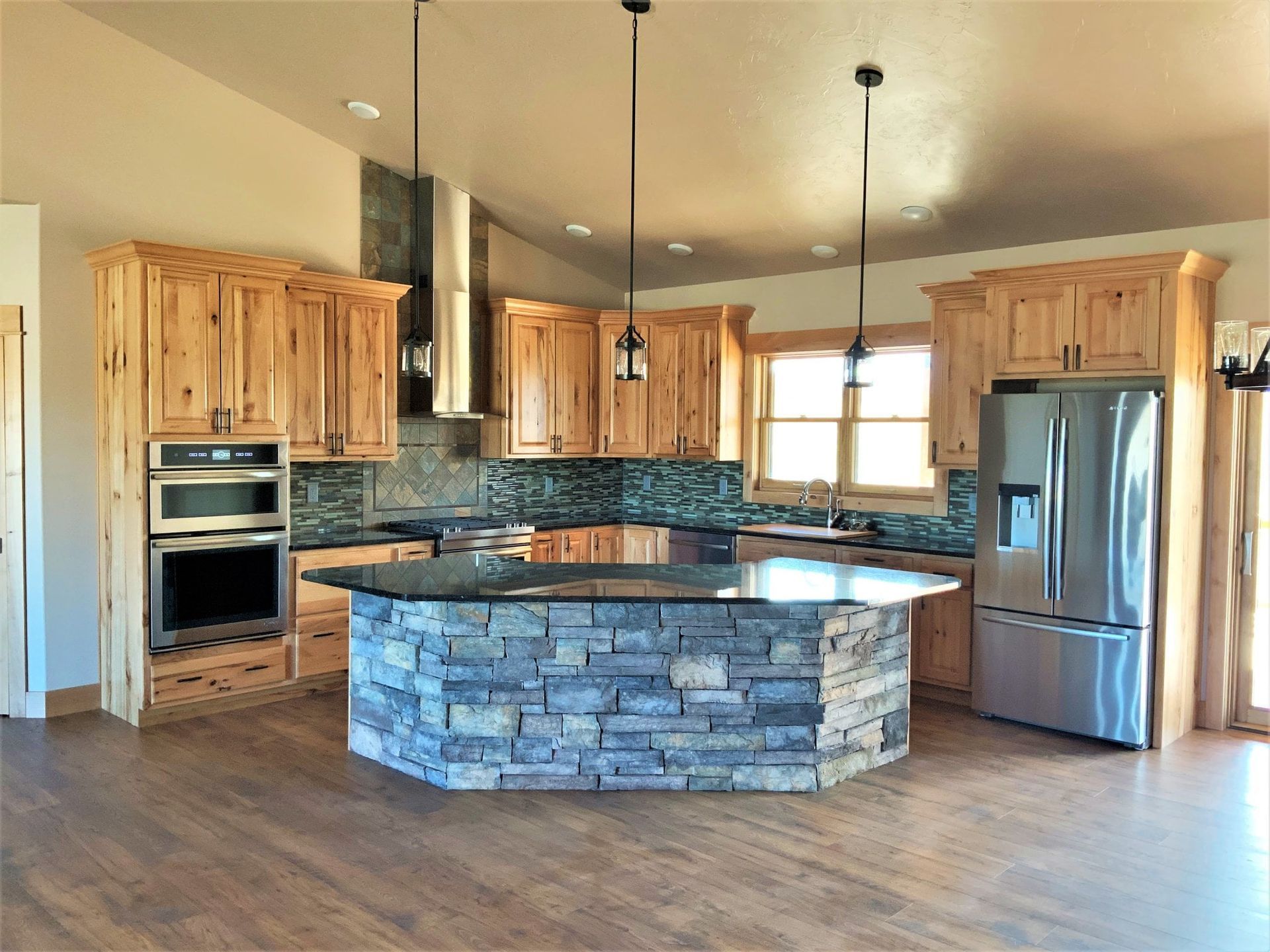 Kitchen with wood cabinets, stone island, stainless steel appliances, and dark countertops.