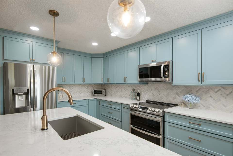 Kitchen with light blue cabinets, stainless steel appliances, and gold fixtures.