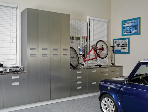 Garage with stainless steel cabinets, a bike, and a blue car.