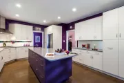Modern kitchen with white cabinets, purple accents, and a large island.