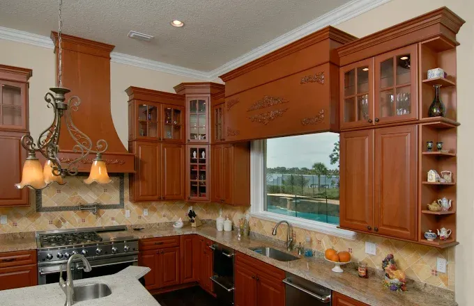 Elegant, wood-toned kitchen with cabinets, stove, sink, and window overlooking a lake.