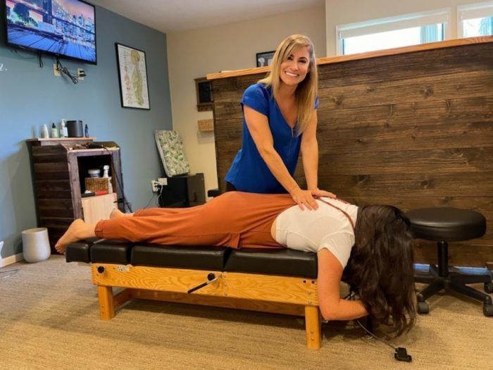 Chiropractor adjusting a patient lying face down on a treatment table in a clinic room