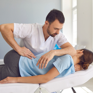 A chiropractor performs a spinal adjustment on a patient lying on a treatment table in a clinic.