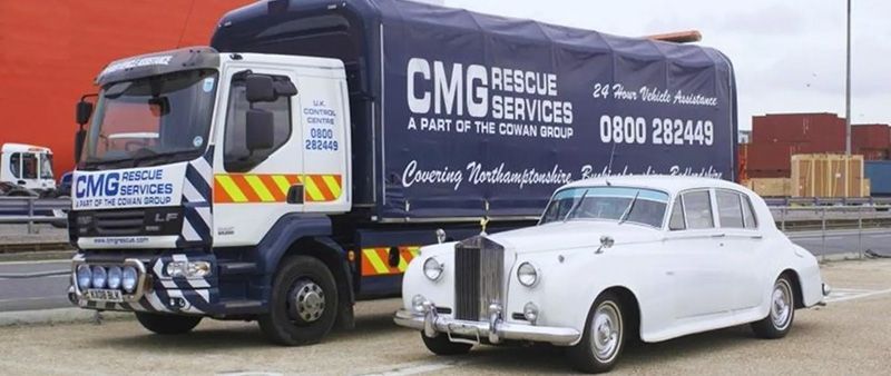 A white car is parked next to a truck that says cmg rescue services