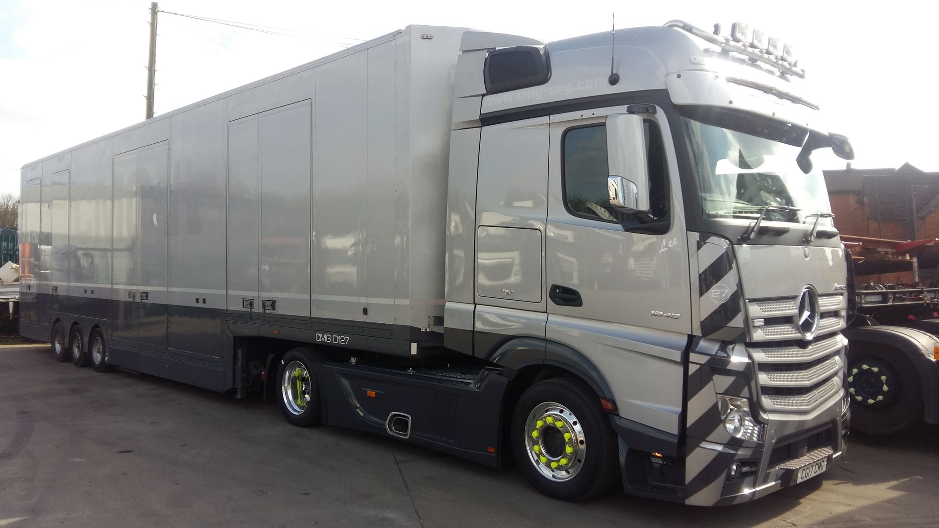A large white truck with a trailer attached to it is parked in a parking lot.