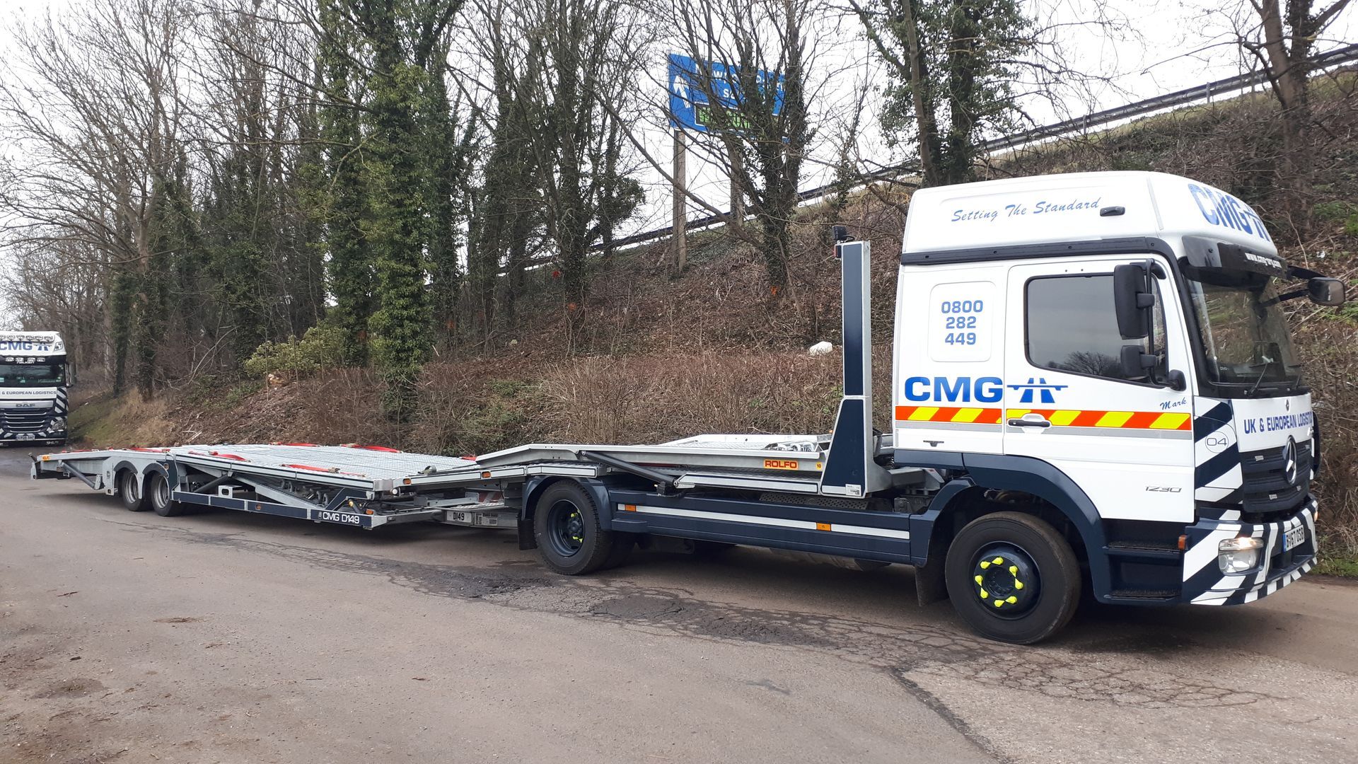 A truck with a trailer attached to it is parked on the side of the road.