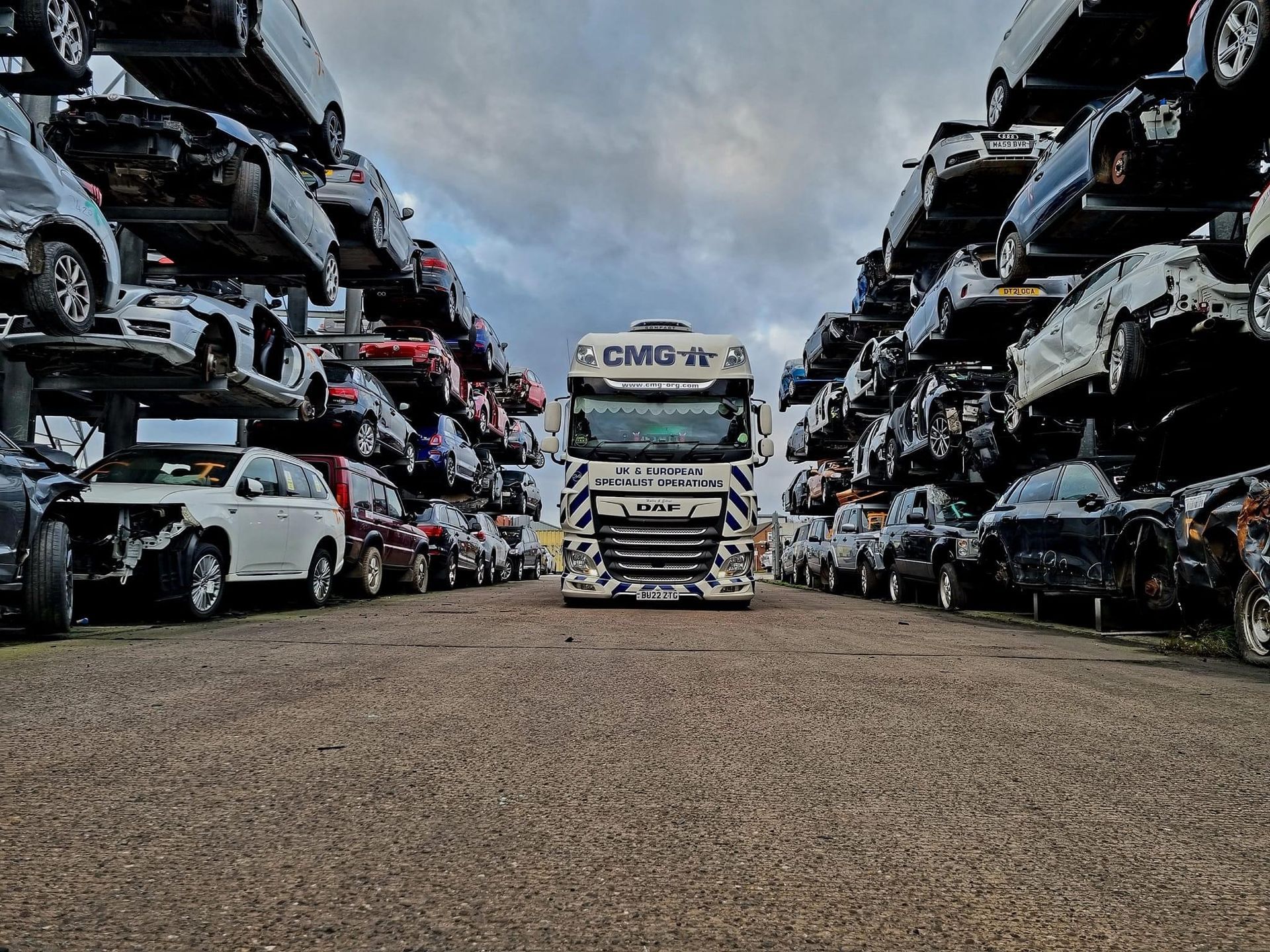 A truck is driving through a parking lot filled with lots of cars.