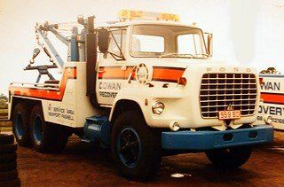an old tow truck is parked in a parking lot .