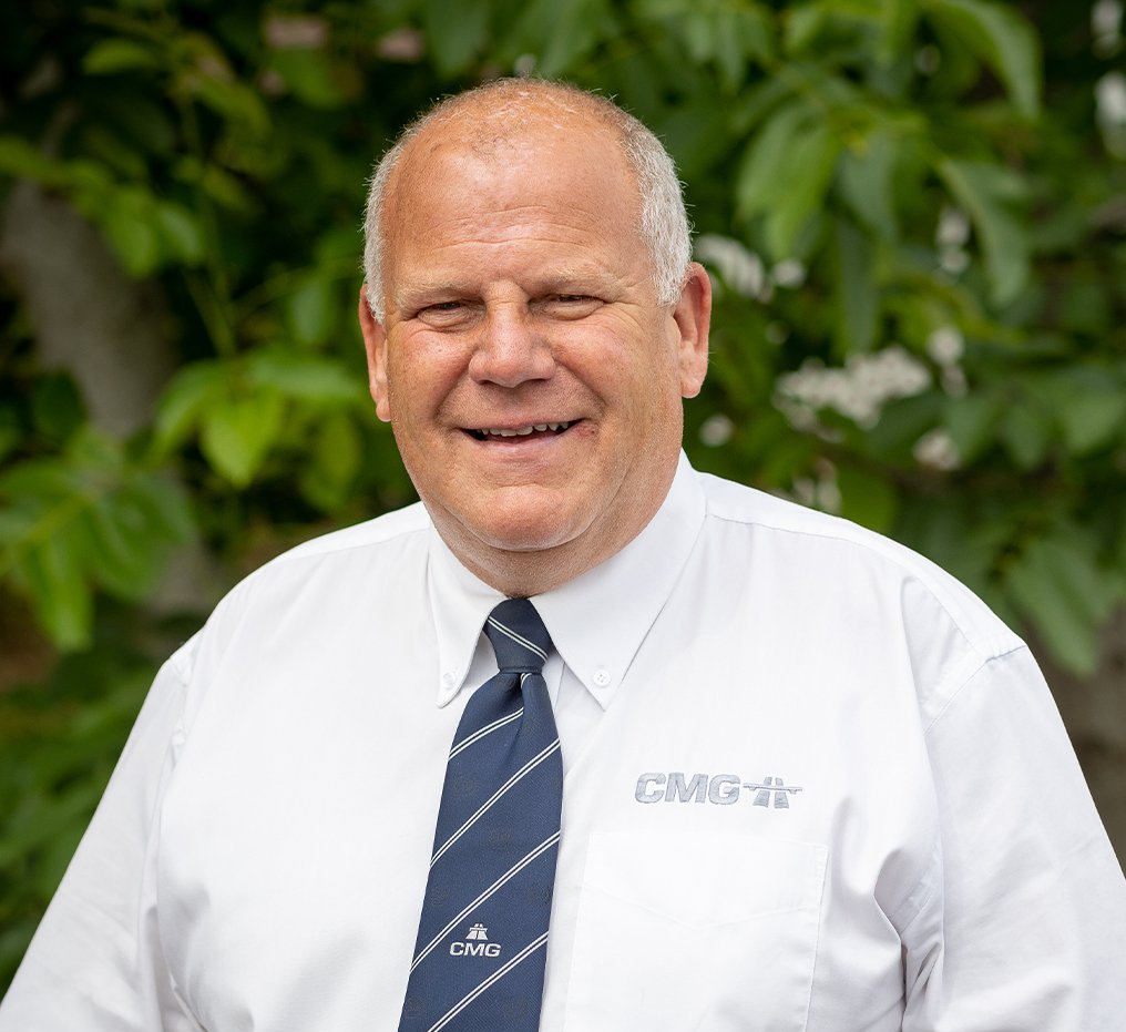 A man in a white shirt and blue tie is smiling for the camera.