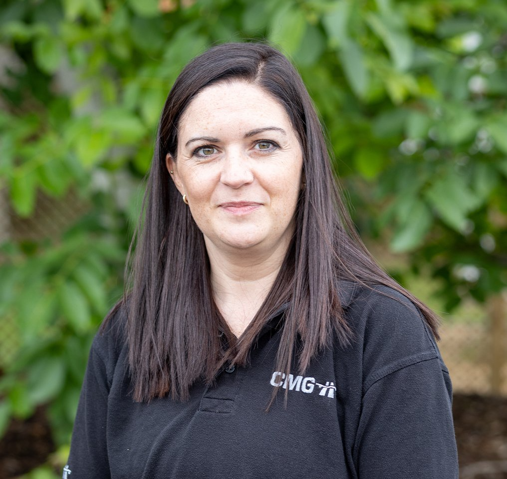 A woman in a black shirt is standing in front of a tree.