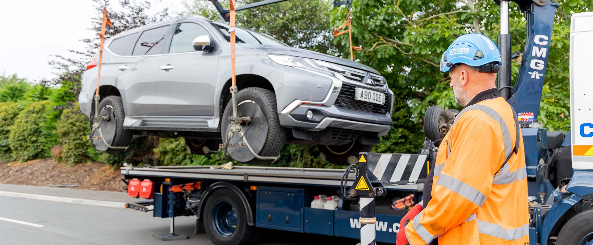 A man is standing next to a tow truck with a car on it.