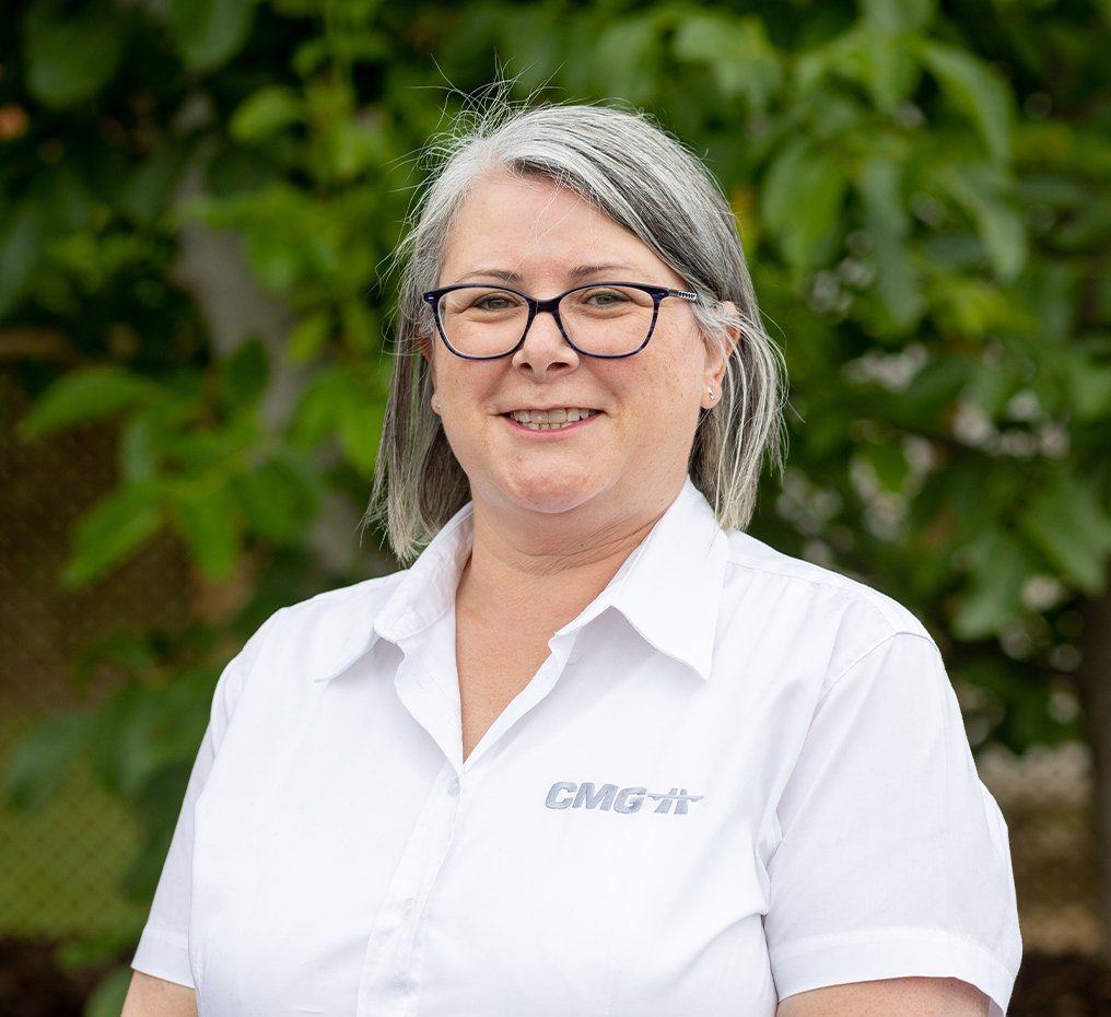A woman wearing glasses and a white shirt is smiling for the camera.