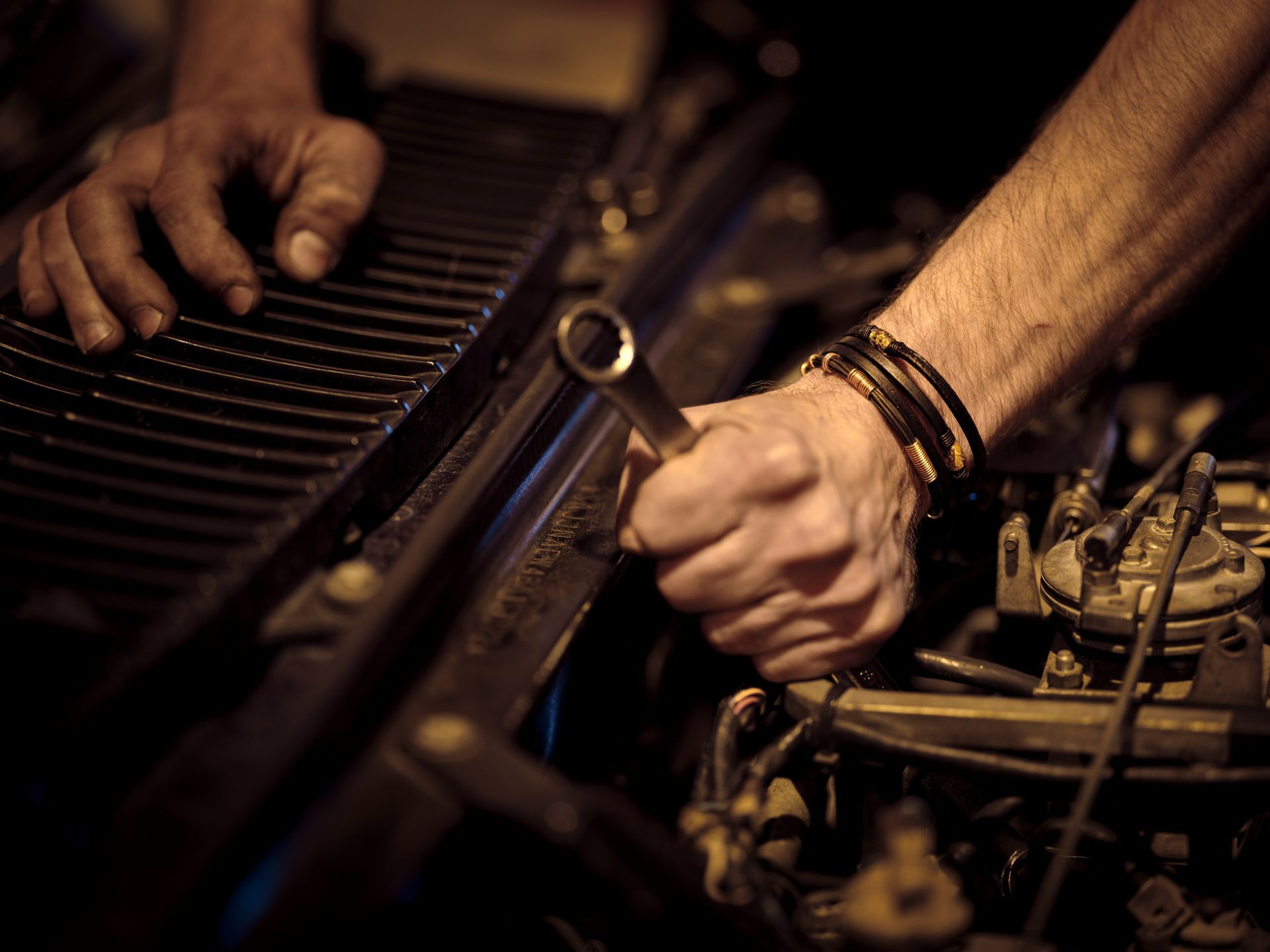 A man is working on a car engine with a wrench.