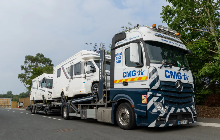 A large truck is carrying a caravan on a trailer.