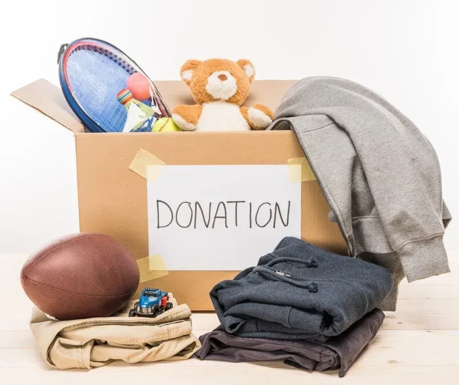 Cardboard donation box with clothes, toys, and sports equipment.