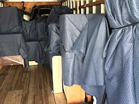 Furniture wrapped in blue moving blankets.