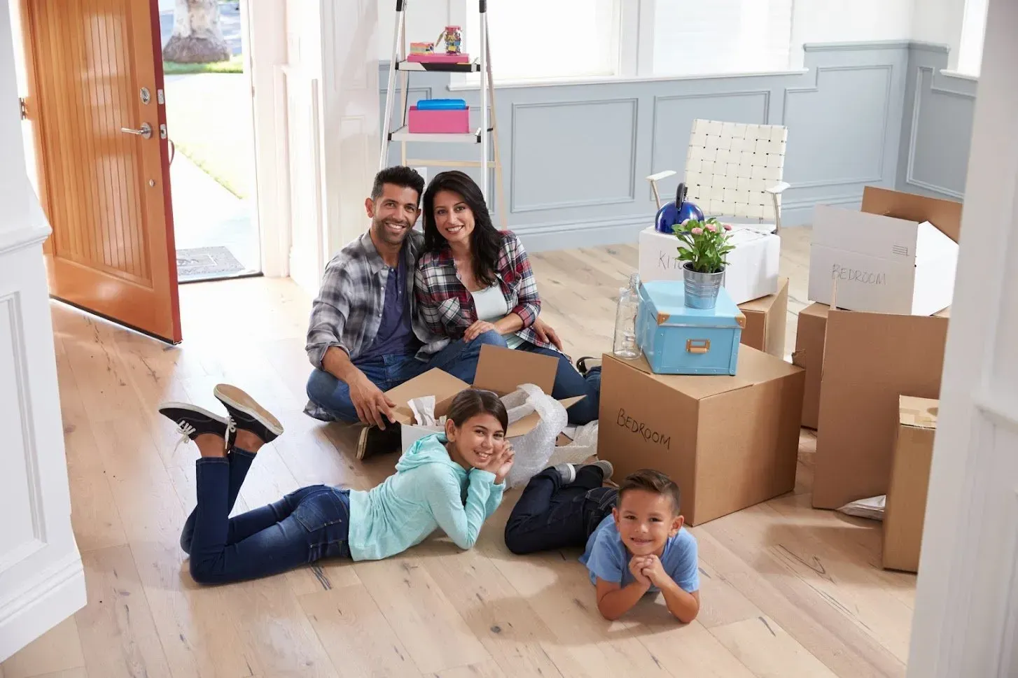 Family sitting among moving boxes in a new home; smiling.