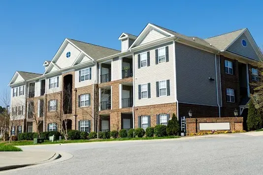 Multi-story apartment building with brick and siding, blue sky.