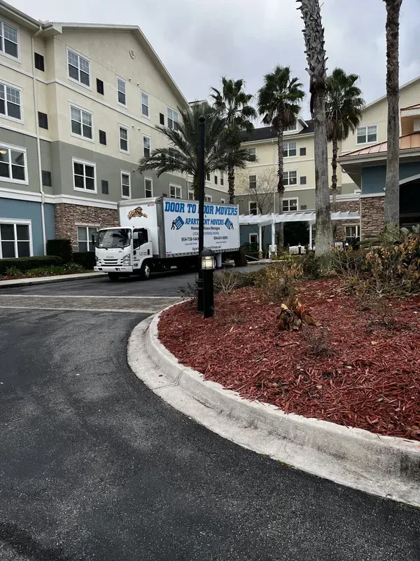 Moving truck parked in front of multi-story apartment building.