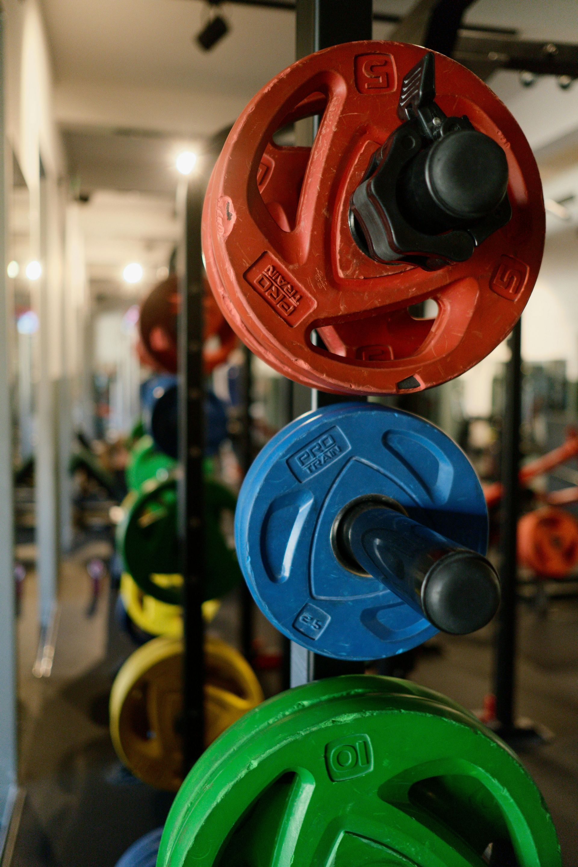 A bunch of colorful weight plates are stacked on top of each other in a gym.