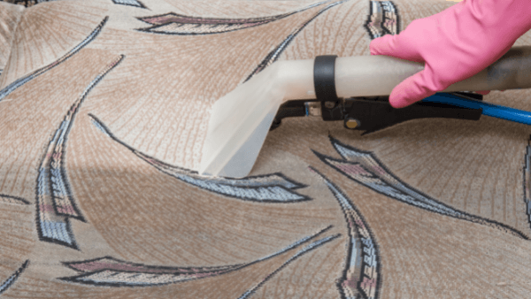 sofa cleaning Hastings. An image of a professional sofa clean taking place. It is a close up image of a pink rubber glove holding the equipment nozzle.