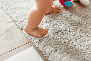 Rug Cleaning Hatings. An image of a baby's feet walking on a clean rug.