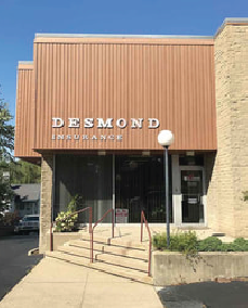 Desmond Insurance building with tan siding, glass door, and stairs leading to the entrance.