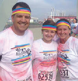 Three people wearing colorful headbands and shirts at a color run.