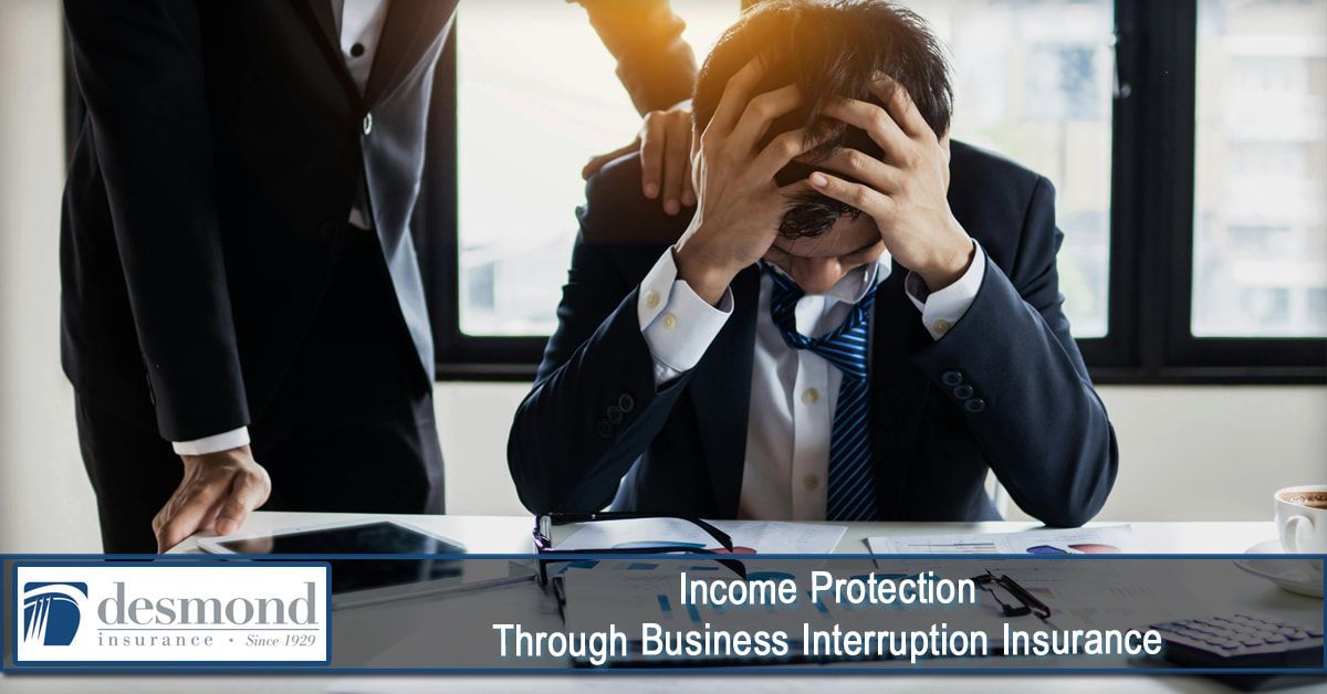 Man in suit stressed, covering face at desk. Another person's hand on his shoulder. Income Protection text.