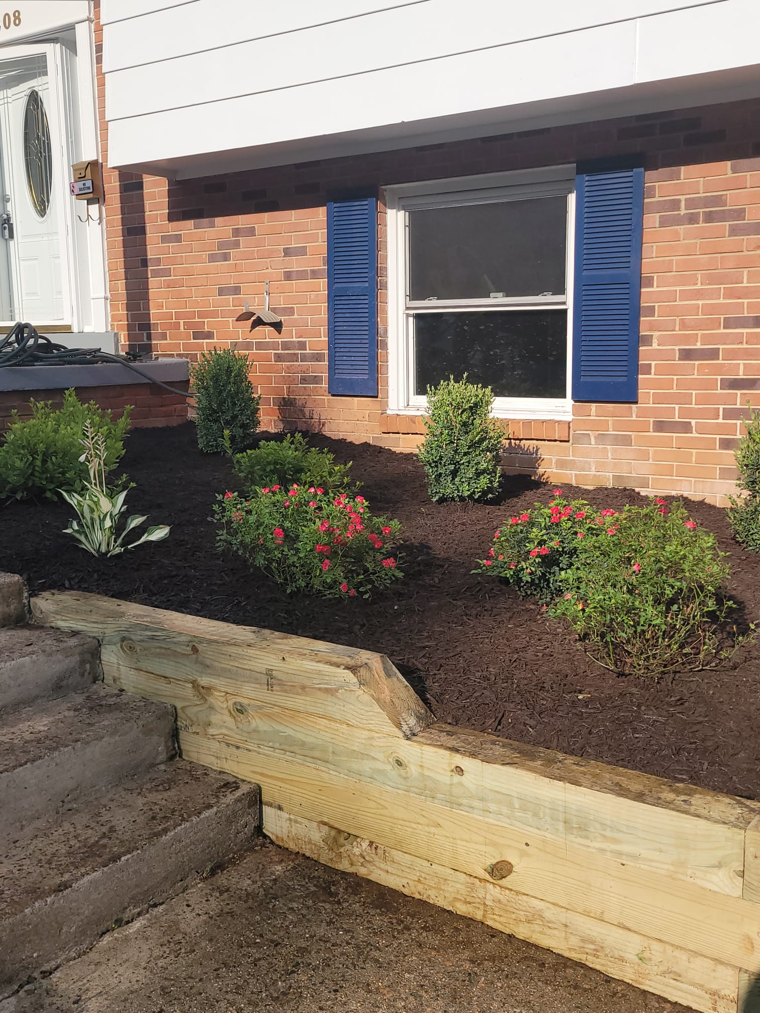 A brick house with blue shutters and a garden in front of it.
