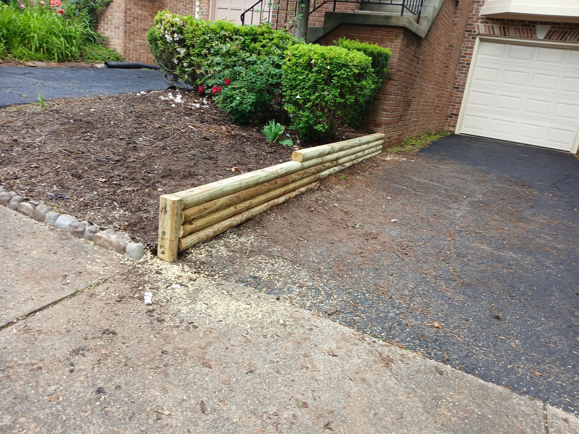 A wooden fence is sitting next to a driveway in front of a house.