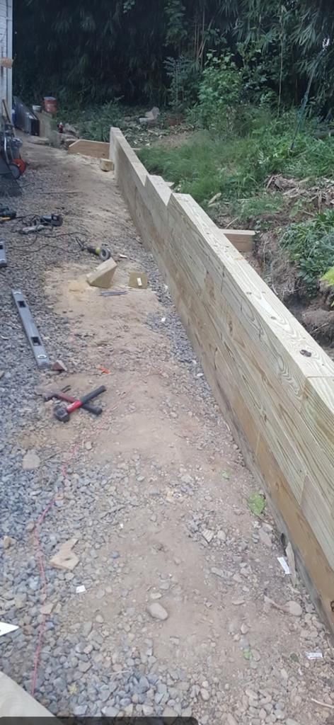 A wooden fence is being built on a gravel road.