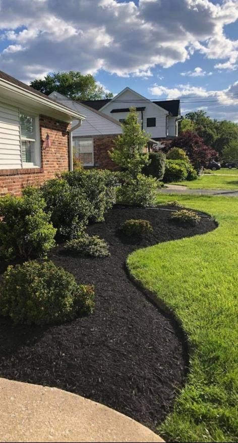 A lush green yard with a brick house in the background.