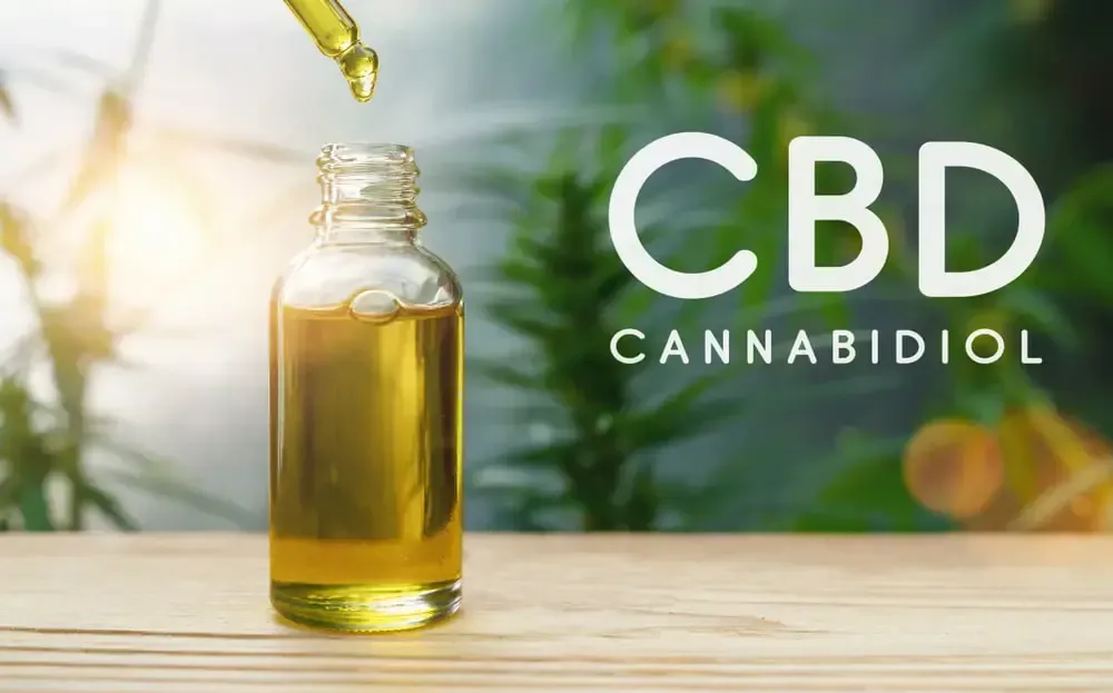Cbd oil is being poured into a bottle on a wooden table.