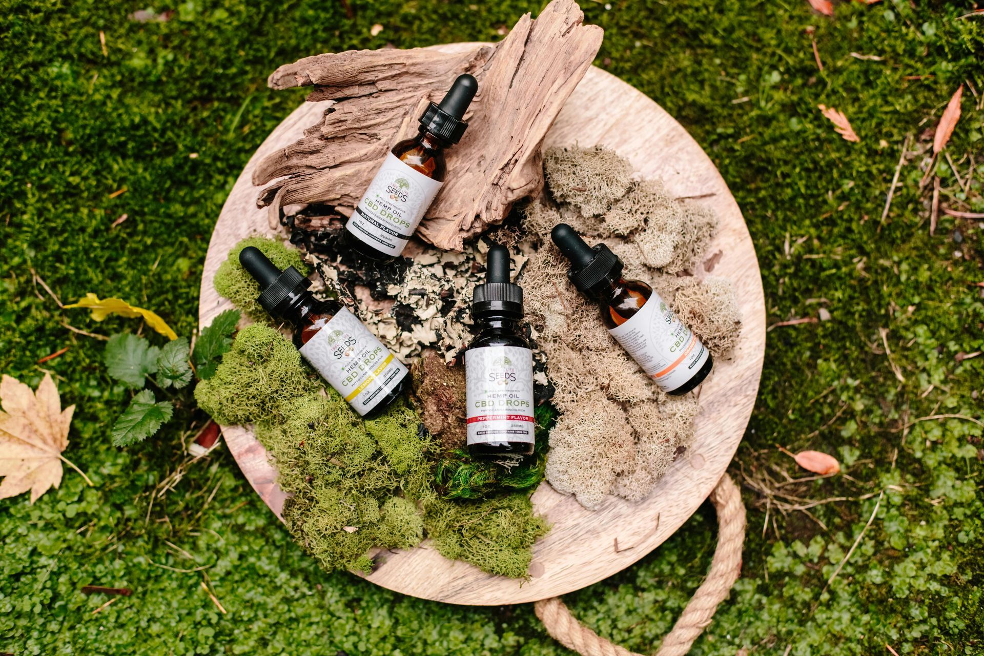 A wooden plate with four bottles of oil on it.