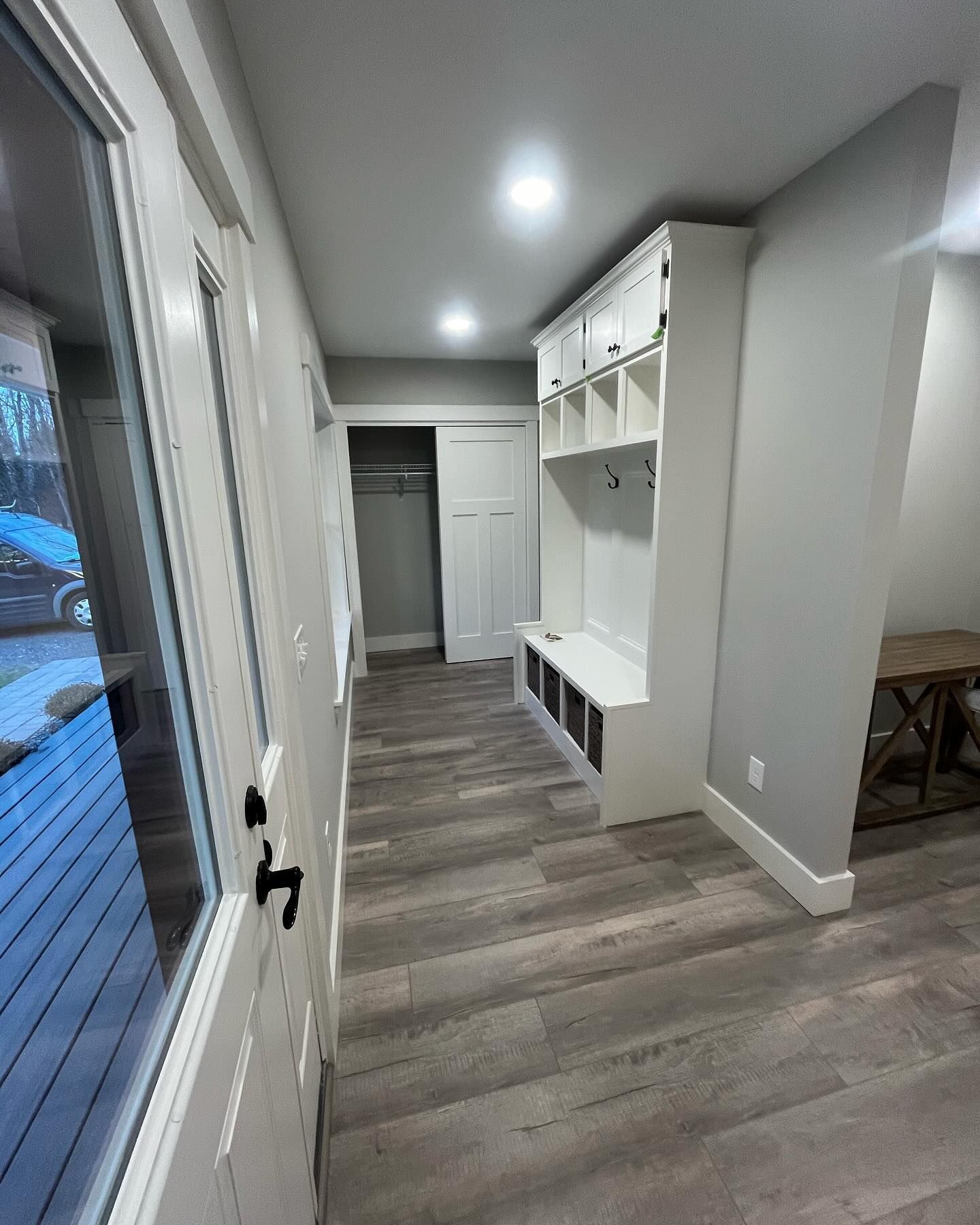 Hallway with white storage bench, lockers, and light gray flooring.