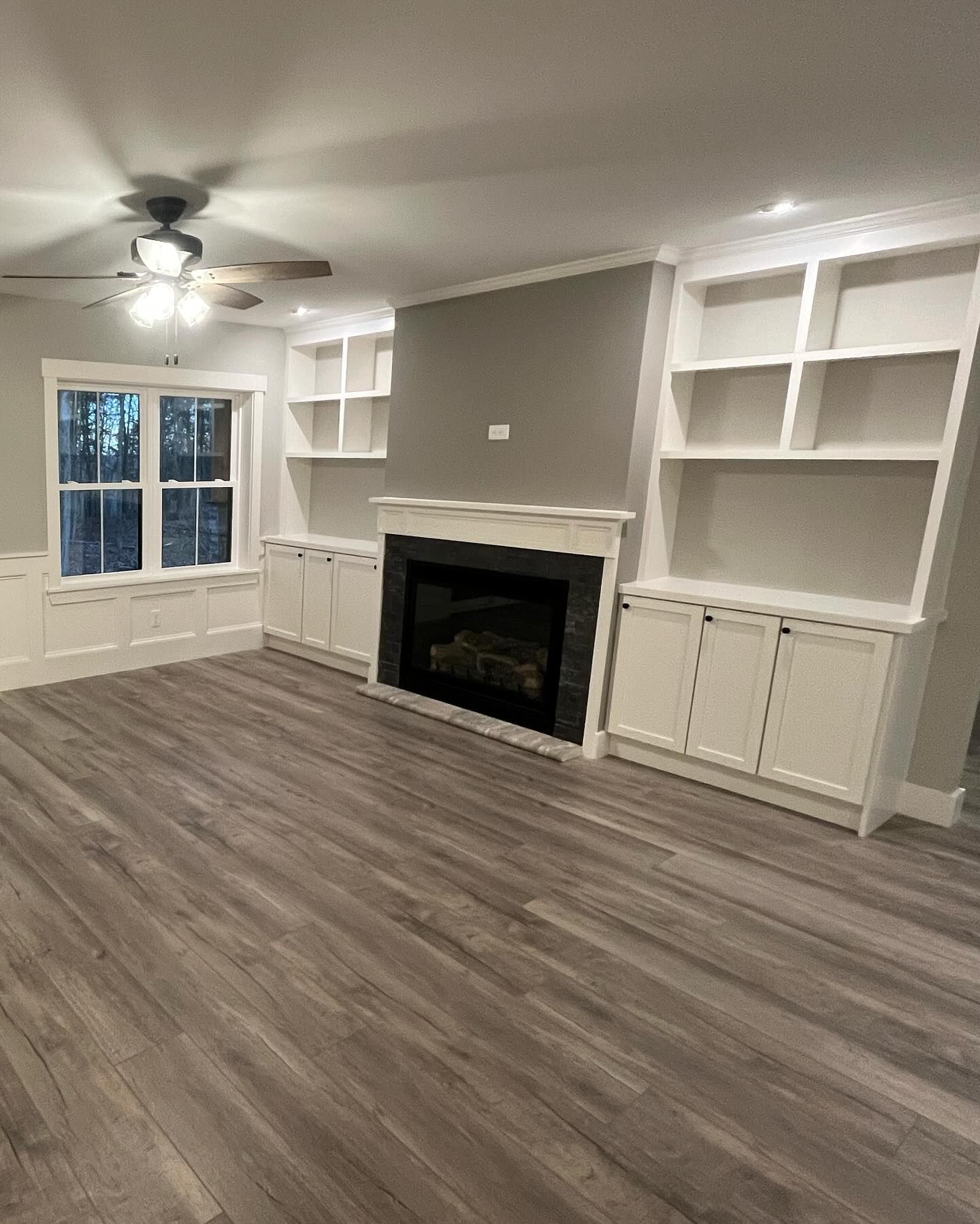 Living room with fireplace, built-in shelves, gray walls, and light wood-look flooring.
