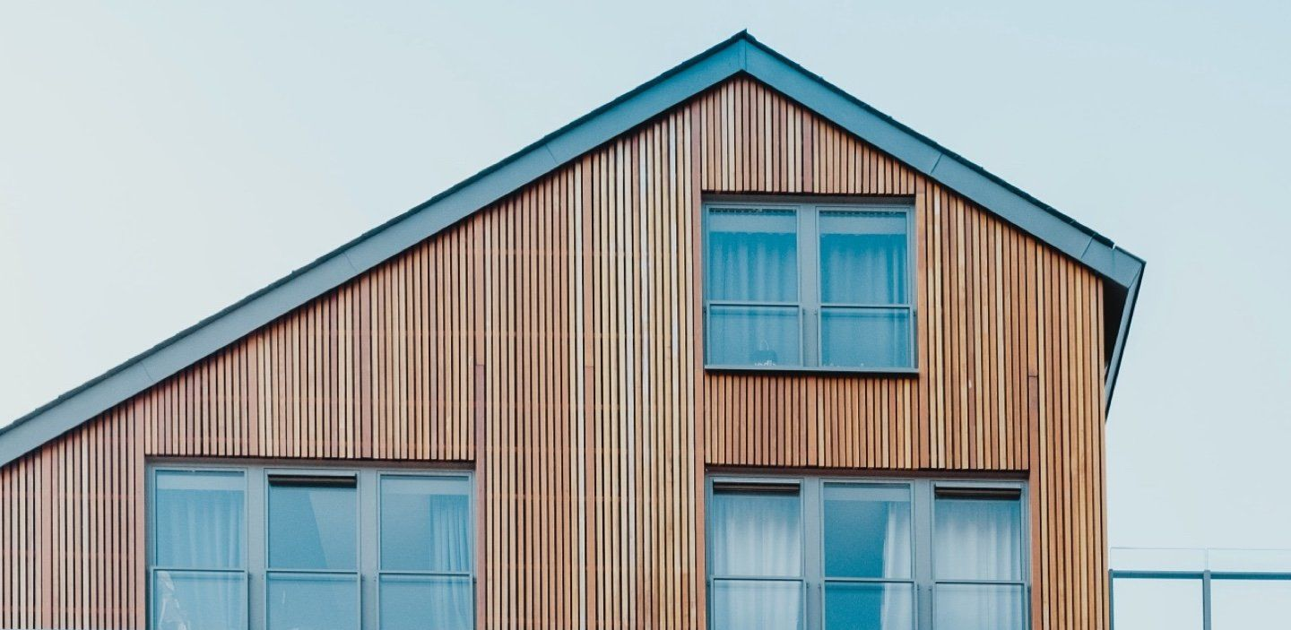 Wooden house with windows and a slanted roof against a clear sky.