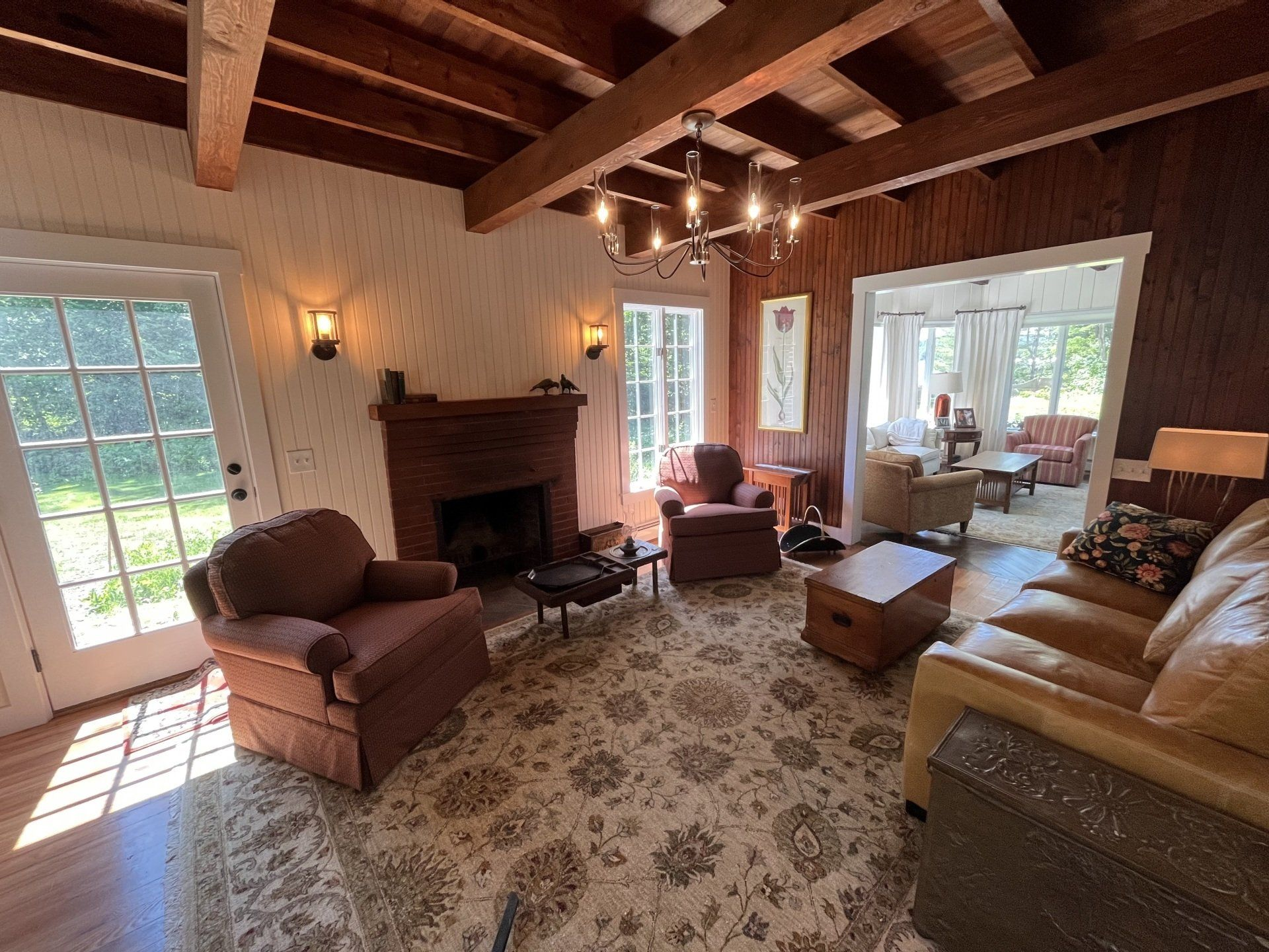 Living room with wood paneling, fireplace, rug, and furniture. A doorway leads to another room.