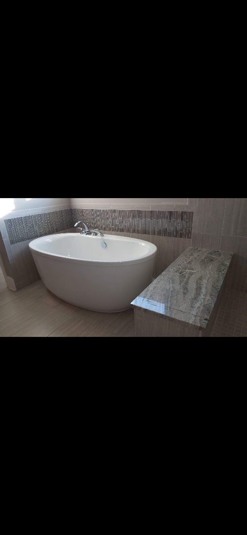 Marble countertop next to white bathtub in bathroom