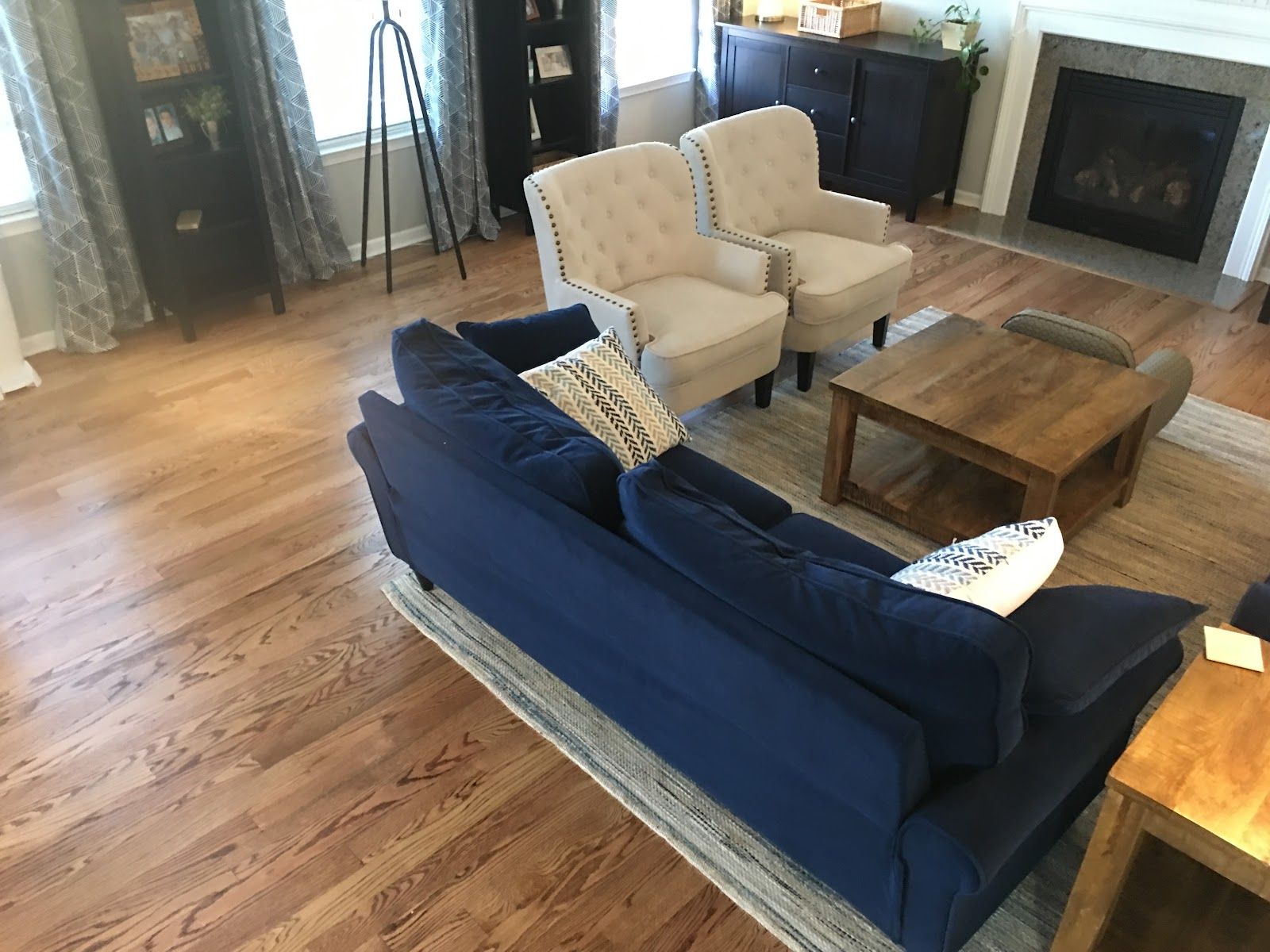 Living room with blue sofa, beige armchairs, wooden coffee table, and fireplace.