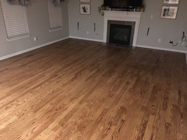 Hardwood floor in a living room with fireplace, gray walls, and white trim.