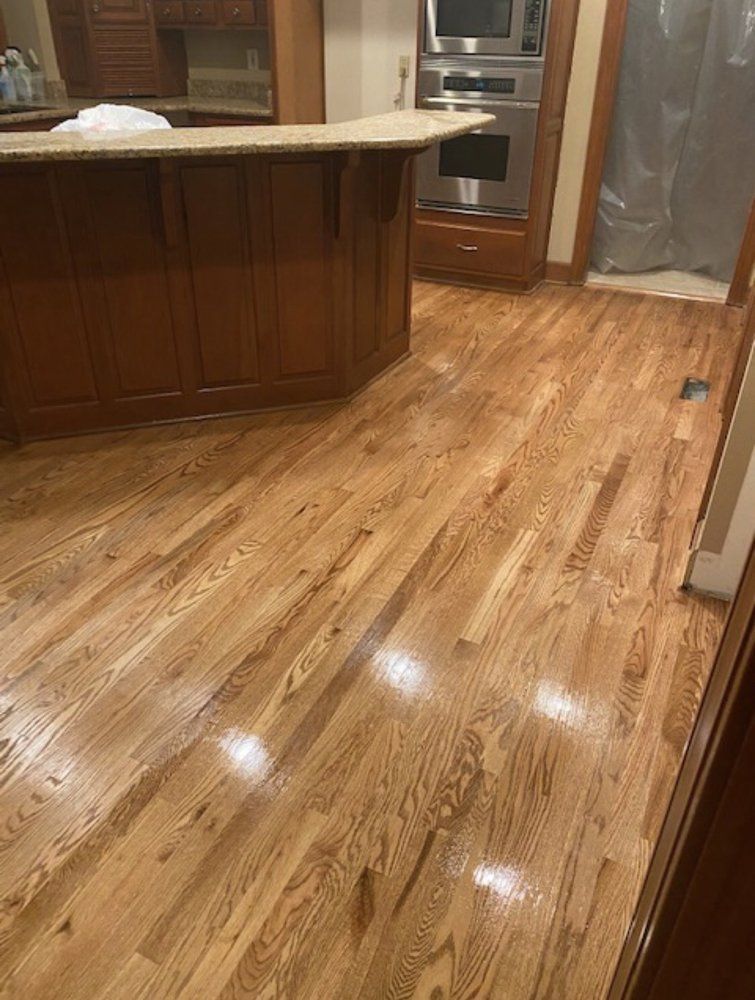 Wooden floors in a kitchen with a brown island and built-in oven.