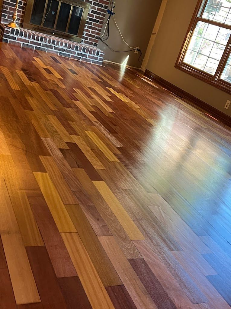 Man sanding a wooden floor in a room, wearing protective gear.