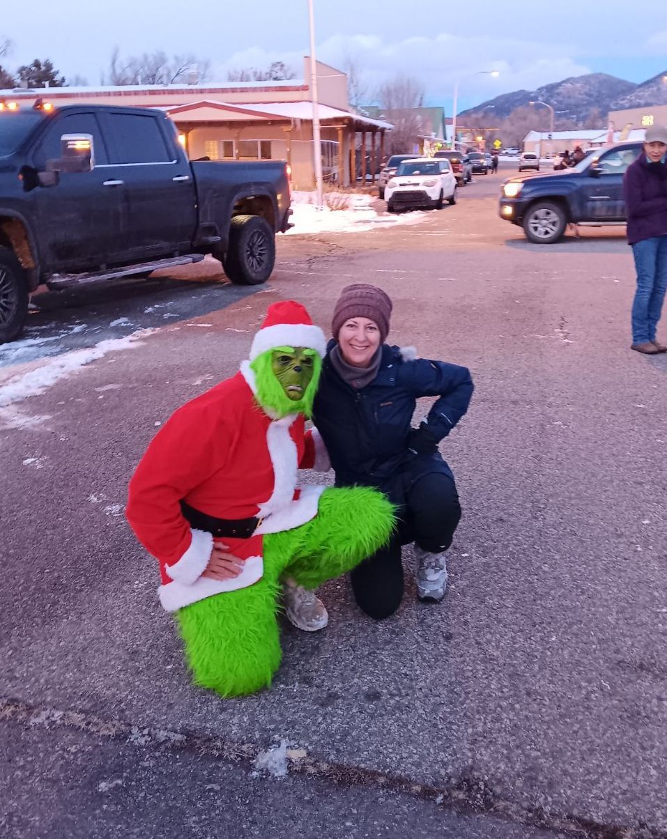 A woman is kneeling next to a man dressed as the grinch