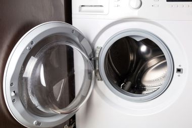 Front-loading washing machine with open door and visible stainless steel drum