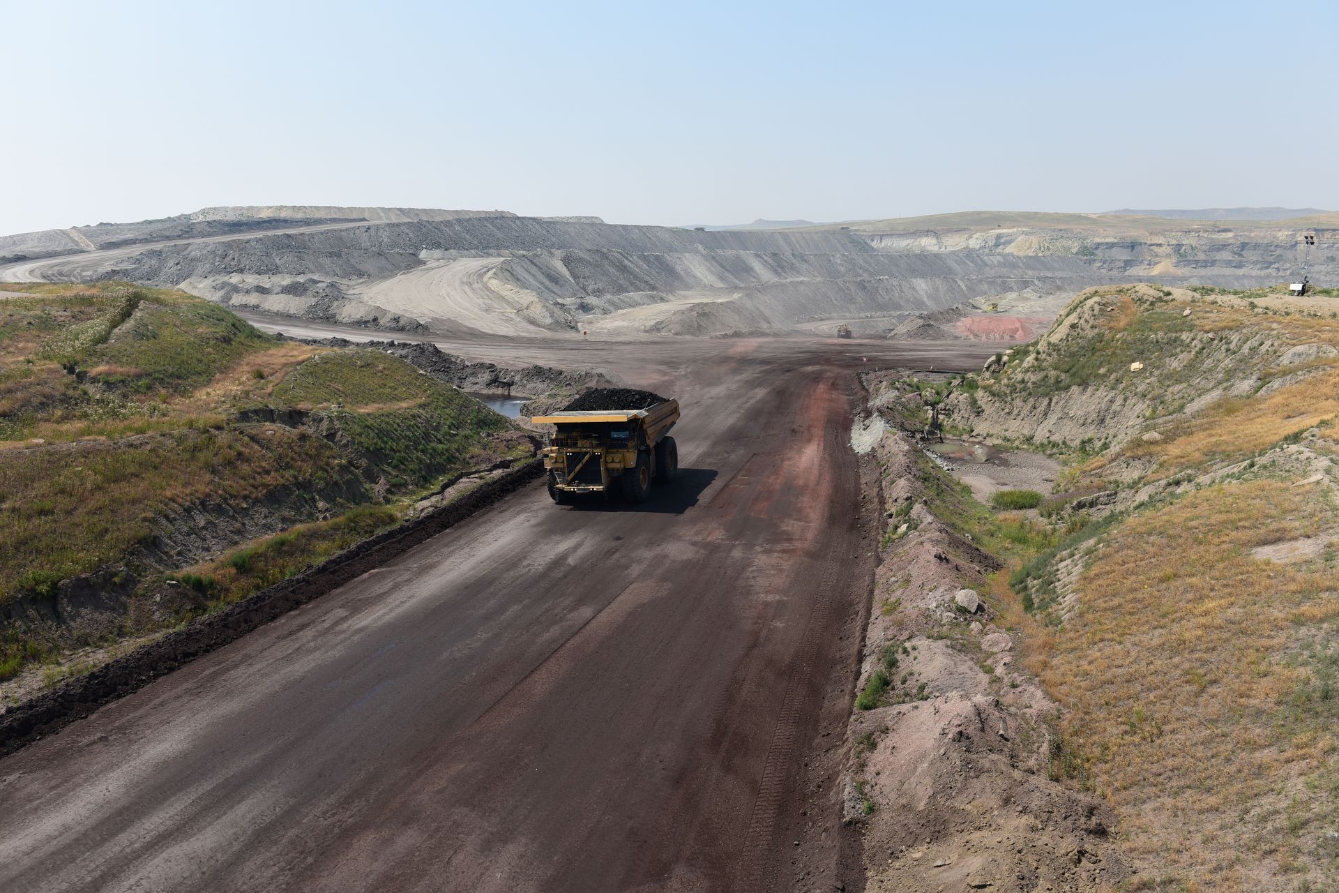 A large dump truck is driving down a dirt road.