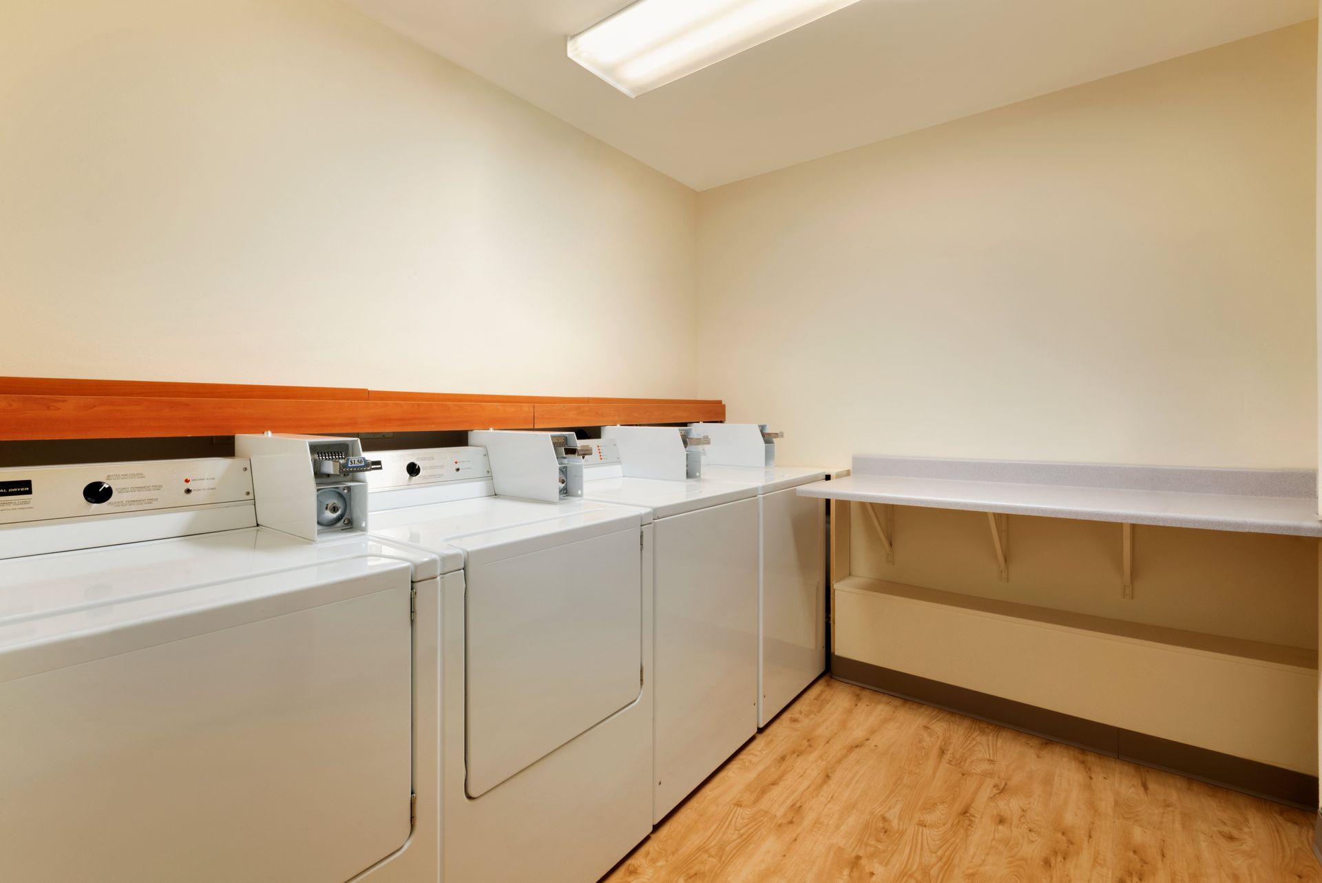 A laundry room with a row of white washers and dryers.