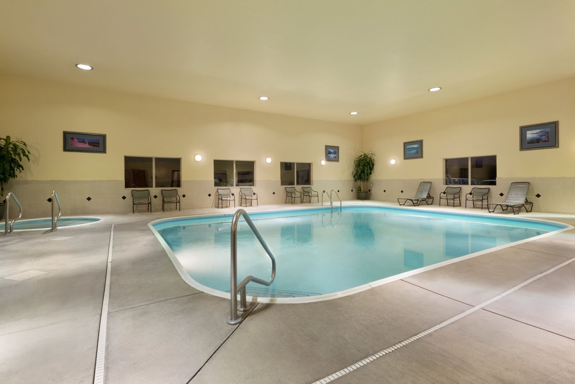 There is a large indoor swimming pool with chairs around it.